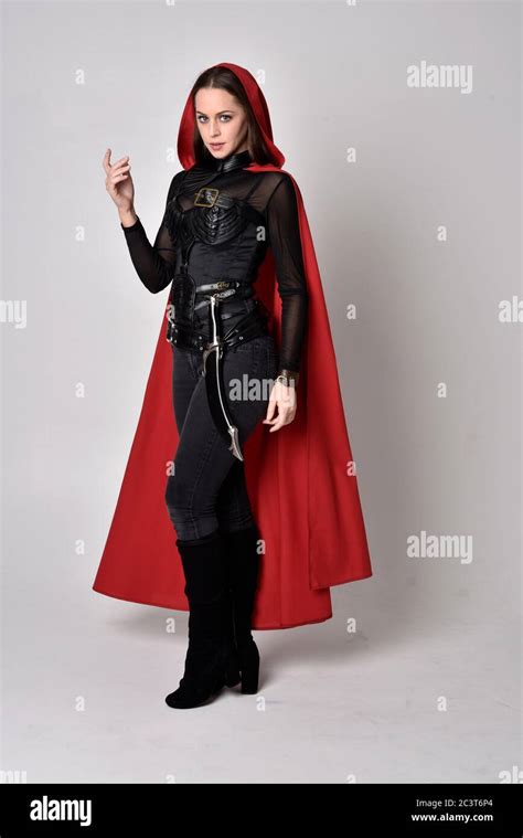 Portrait Of Brunette Girl Wearing Black Leather Catsuit And Red Cloak Full Length Standing Pose