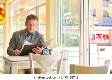 Mature Customer Reading Menu While Sitting Stock Photo