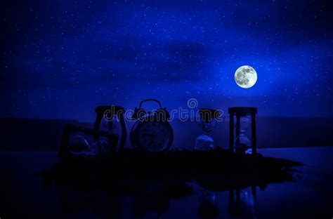 Time Concept With A Hourglass At Night With Moon Or Sand Passing Through The Glass Bulbs Of An