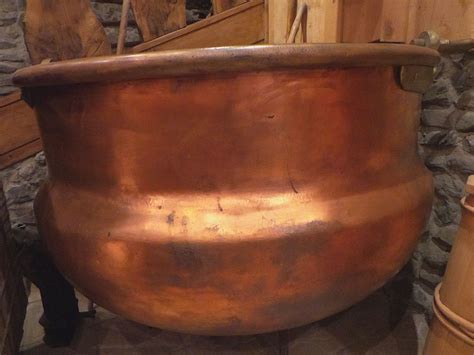 A Large Copper Pot Sitting On Top Of A Stone Floor