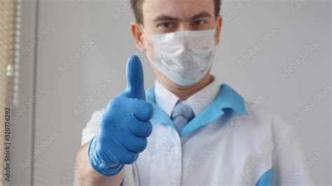 Thumbs up symbol by smiling young confident doctor. Health care concept ...