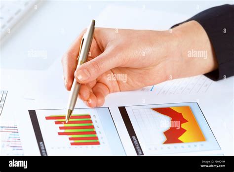 Close Up Of Male Hand Holding Pen And Pointing At Graphs Stock Photo