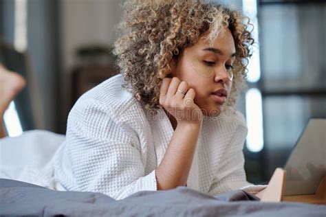 Young Serene Woman In White Bathrobe Relaxing On Bed And Looking In