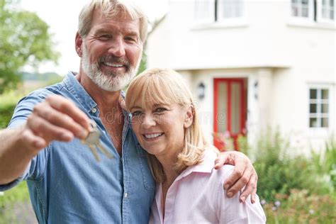Portrait Of Mature Couple Standing In Garden In Front Of Dream Home In