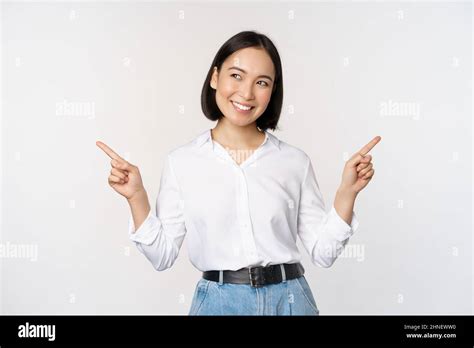 Image Of Beautiful Asian Woman Pointing Fingers Left And Right Making Decision Showing Two