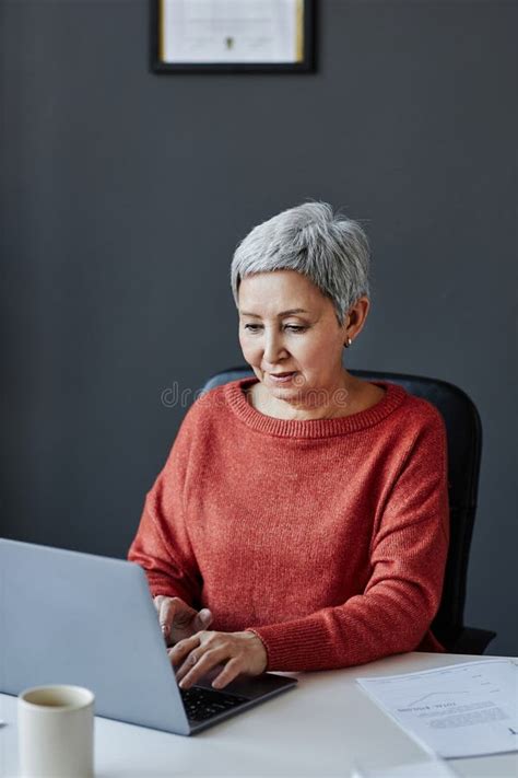 Senior Businesswoman Using Laptop At Workplace In Office Stock Photo