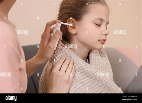 Mother Spraying Medication Into Daughters Ear In Living Room Stock