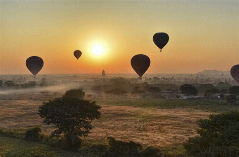 Hot Air Balloons Over Landscape With Distant Temples At Sunset Bagan Myanmar Stock Photo