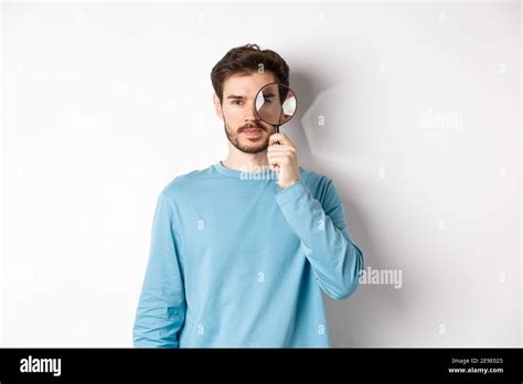 Man Searching For Something Looking Through Magnifying Glass At Camera