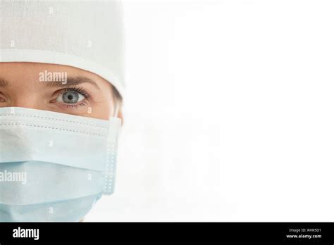 Closeup Portrait Of Female Doctor Wearing Surgical Mask And Cap Against