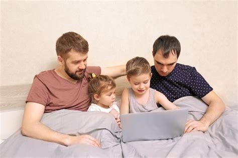 Pareja gay masculina con niños descansando en la cama en casa Foto Premium