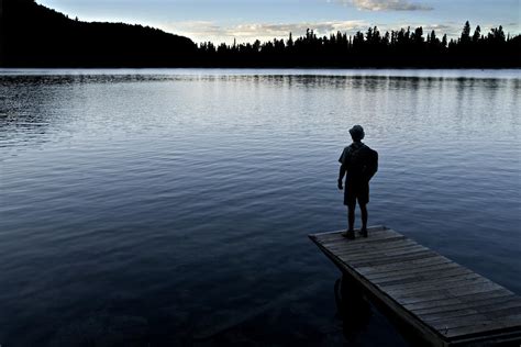 A Man Looking Across A Lake Into By Dawn Kish