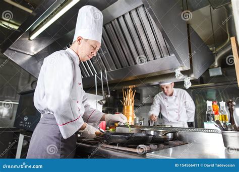 Cocinero En Cocina Del Restaurante En La Estufa Con La Cacerola