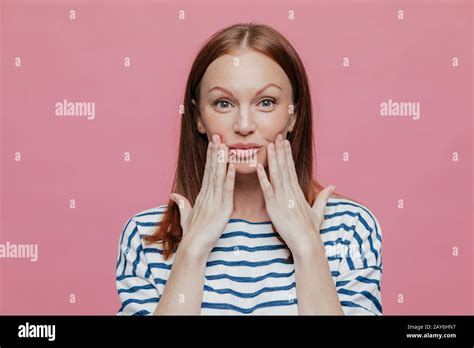 Headshot Of Freckled Pretty Woman Keeps Hands Near Lips Has Minimal Make Up Healthy Skin