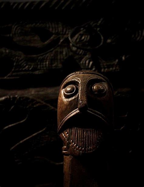 A Close Up Of A Wooden Mask In The Dark