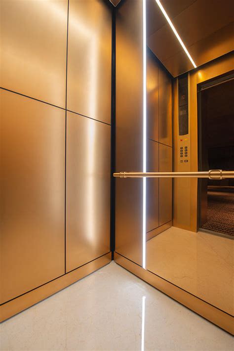 An Elevator With Gold Walls And White Flooring Is Illuminated By Bright