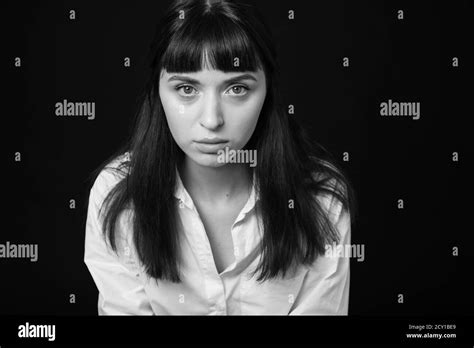 Studio Portrait Of A Pretty Brunette Woman In A White Shirt Against A Plain Black Background