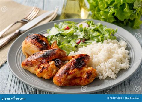 Grilled Chicken Wings And Drumsticks Served With Boiled Rice And Salad