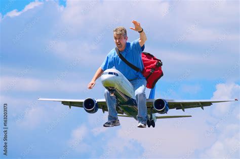 A Happy Man With A Red Duffel Bag Is Waving As He Flies Through The Air