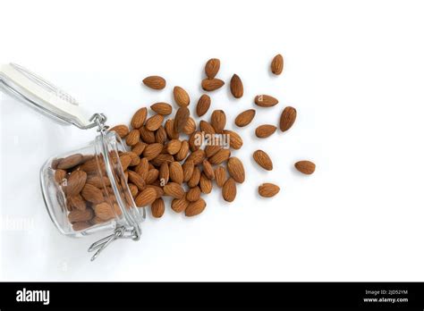 Peeled Almonds Nuts Poured Out Of Glass Jar On White Background