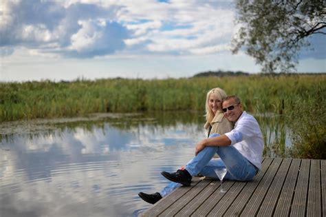 Premium Photo Portrait Of Couple Sitting On Pier Over Lake