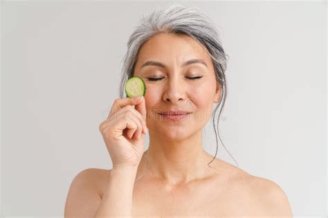 Mature Shirtless Woman With Grey Hair Showing Piece Of Cucumber Stock
