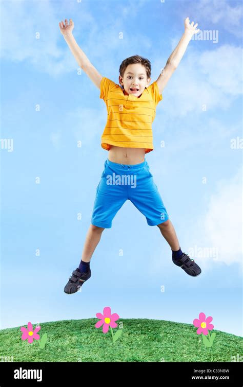 Image Of Happy Boy Jumping On The Grass And Looking At Camera Stock