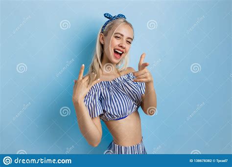 Joyful And Excited Beautiful Blonde Girl In Summer Outfit Pointing At Camera Standing Over
