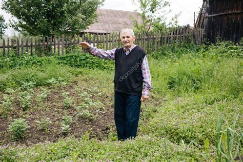 Un Abuelo Feliz Est De Pie Y Muestra Un Huerto En El Patio Del Pueblo