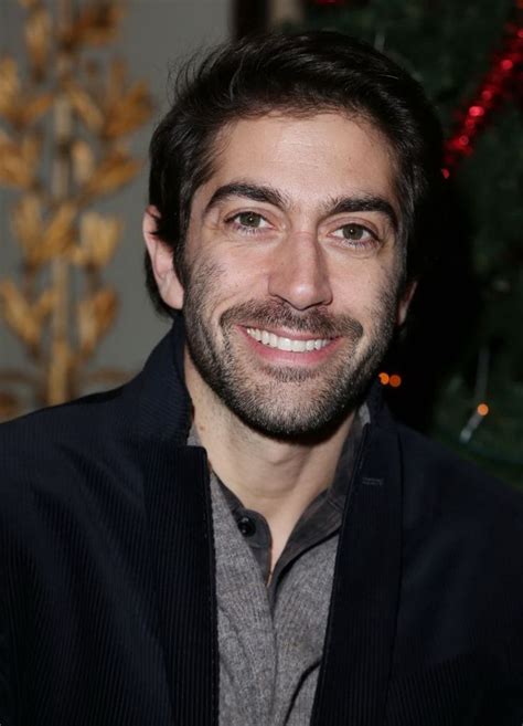 A Man Smiling For The Camera In Front Of A Christmas Tree