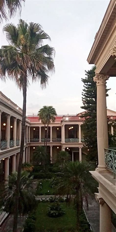 A Courtyard With Palm Trees In The Foreground And Two Balconies On