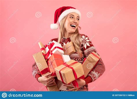 Lovely Caucasian Woman In Xmas Outfit Holding Stack Of Wrapped Christmas Ts On Pink