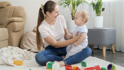 Cute Smiling Baby Boy Sitting On Mothers Lap And Looking On Colorful