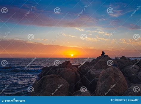 Siluetta Di Un Uomo Che Si Siede Sulle Rocce Che Godono Del Tramonto