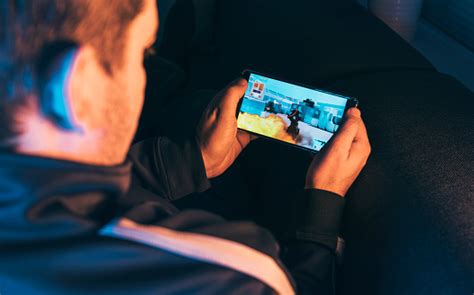 Leisure Gamer Plays Action Video Game On Mobile Phone At Night Stock