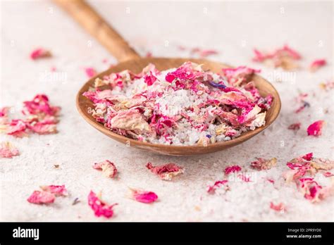 See Salt Wih With Dried Flower Petals In Wooden Scoop On Pink Marble