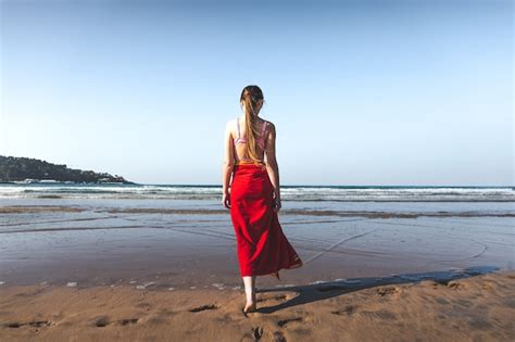 Mujer Joven Vistiendo Una Toalla Roja Y Un Bikini Rosa Caminando Al Borde Del Agua En La Playa