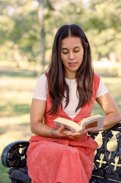 Joven Latina Leyendo Un Libro Sentado En Una Banca Del Parque