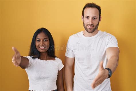 Interracial Couple Standing Over Yellow Background Smiling Friendly