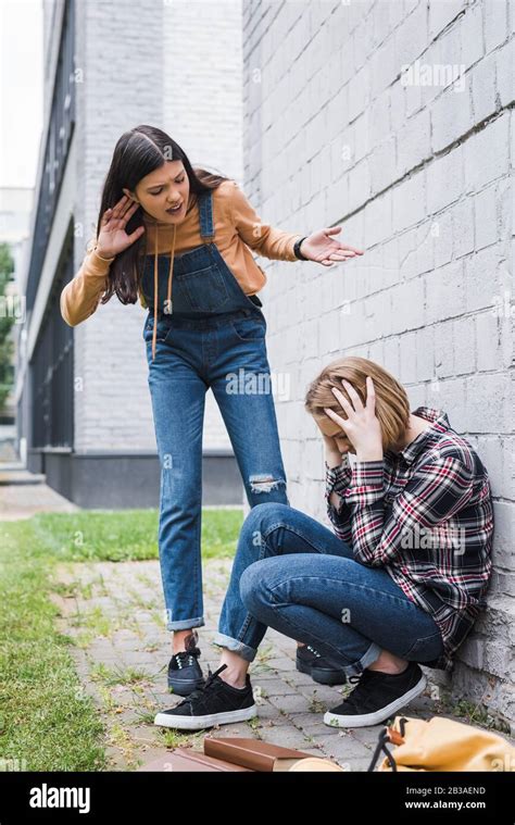 Aggressive And Brunette Teenager Bulling Blonde And Scared Teenager Stock Photo Alamy