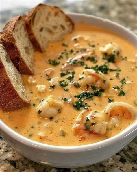 A White Bowl Filled With Shrimp Chowee Next To A Piece Of Bread On Top