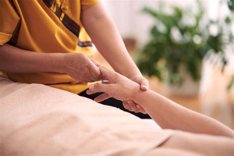 Premium Photo Young Professional Masseuse In Yellow Uniform Sitting