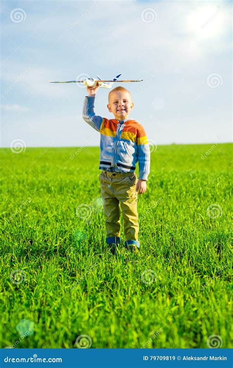 Muchacho Feliz Que Juega Con El Aeroplano Del Juguete Contra El Cielo