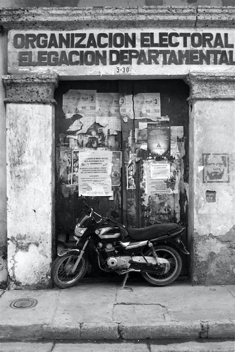 Grayscale Photography Of Motorcycle Parked In Front Of Wooden Door