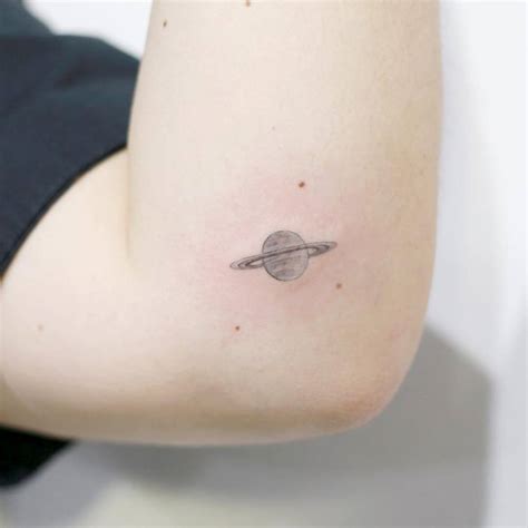 Fine Line Saturn Tattoo On The Left Elbow