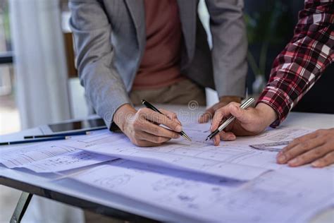 Engineer Pointing At Blueprint And Using Laptop To Draw Building Design