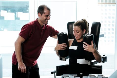 Premium Photo Blonde Girl Working Out With Her Personal Trainer On A Gym Machine