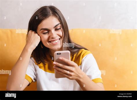 Cute Long Haired Brunette Girl Sitting On The Yellow Sofa In The Light