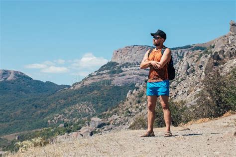 A Man Tourist Stands On A Rock Against The Backdrop Of A Cliff And