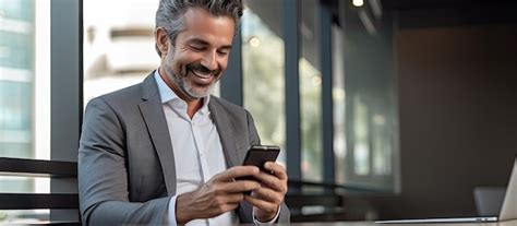 Premium Photo Mature Businessman Using Mobile App And Laptop In Office Smiling
